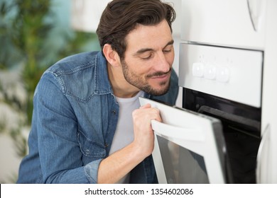 Man Enjoying The Smell From The Open Oven Door