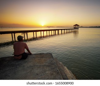 A Man Enjoying Sunset Scenery At Seascape. Soft Focus On Some Part Of Image Due To Slow Shutter Speed Shot.