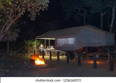 Man Enjoying A Wine Outside Of Off Road Camper Trailer In The Dark Next To S Small Glowing Campfire.