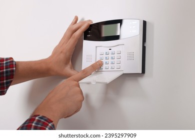 Man entering code on security alarm system at home, closeup - Shutterstock ID 2395297909