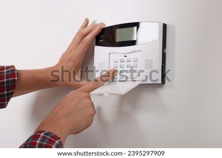 Man entering code on security alarm system at home, closeup