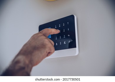 Man entering code pin on home alarm system keypad.