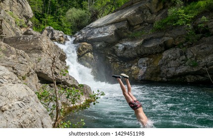 Man Entering Water After A Dive In Front Of A Waterfall