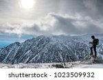 Man with equipement on the edge, hiking mount Washington in winter, looking over the ravine. New Hampshire, USA