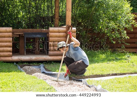 man evens gravel on the path with rake