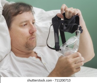 Man Examines A CPAP Mask