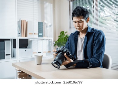 A Man examining camera at desk in bright office setting - Powered by Shutterstock