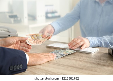 Man exchanging money at cash department window, closeup