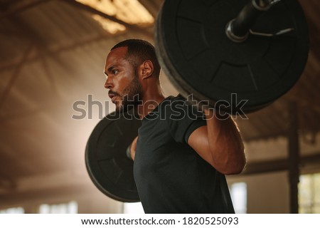 Man exercising with barbell. Male bodybuilder doing weight lifting workout at gym.