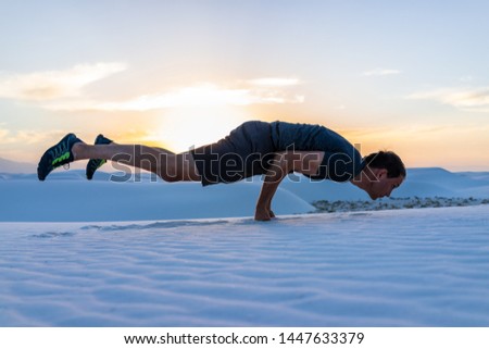 Man exercising doing shelf exercise balancing on fists in white sands dunes national monument in New Mexico view of sunset
