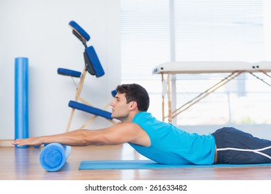 Man exercising with foam roller in fitness studio
