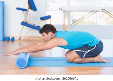Man exercising with foam roller in fitness studio
