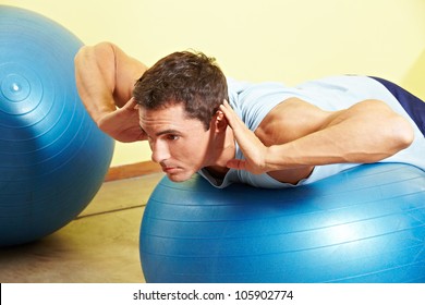 Man Exercising His Back On Gym Ball In Fitness Center