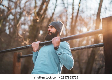 Man is  exercising  pull -ups  in the park. - Powered by Shutterstock