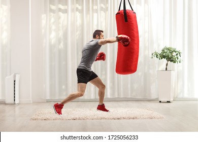 Man Exercising Punching Bag With Boxing Gloves At Home