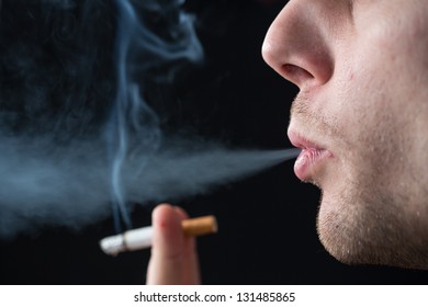 Man exhaling cigarette smoke on black background - Shutterstock ID 131485865