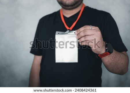 Man at an exhibition or conference showing a blank security identity name card on a lanyard, blank id card badge. Badge name tag, lanyard. Conference, event, convention vip pass
