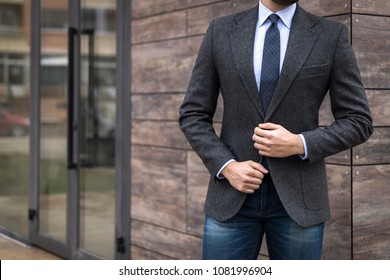 Man in expensive custom tailored suit posing outdoors in front of background