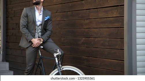 Man in expensive custom tailored suit sitting on bicycle and posing outdoors