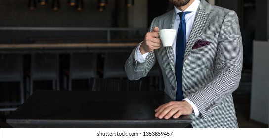 Man In Expensive Custom Tailored Suit Standing And Drinking Coffee And Posing Indoors