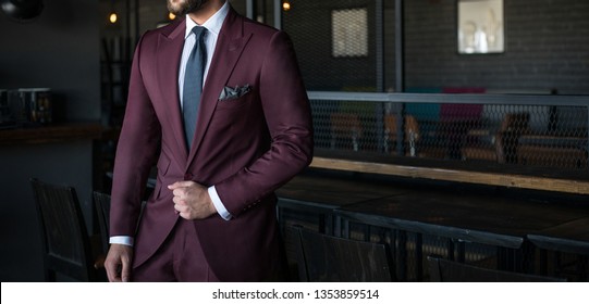 Man In Expensive Custom Tailored Suit Holding His Jacket And Posing Indoors