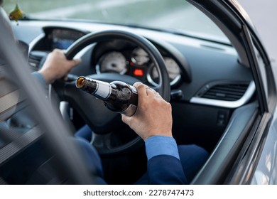 A man in an expensive suit drinks beer at the wheel of a car causing the danger of an emergency. A businessman drinks while driving. Drunk driver concept - Shutterstock ID 2278747473