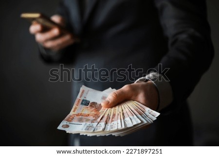 a man in an expensive suit holds a lot of money in his hand, Russian rubles, bills five thousand rubles