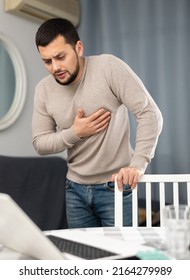 Man experiencing chest pain after working long hours on laptop at home - Shutterstock ID 2164279989