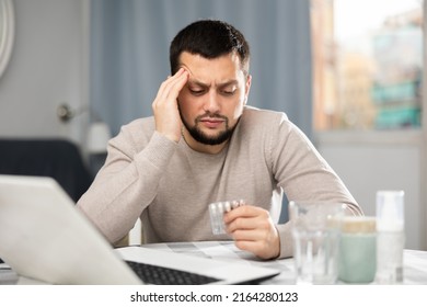Man experiencing headache after working long hours on laptop at home - Shutterstock ID 2164280123