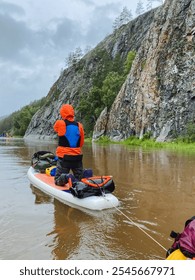 A man expertly pulls a vibrant and brightcolored kayak down a tranquil and serene river, skillfully aided by the gentle current, surrounded by picturesque beautiful nature and an expansive blue sky
