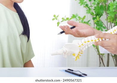 A man explaining in a skeleton model and a woman in a patient - Powered by Shutterstock