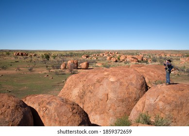 Man, explorer or geologist with binoculars looking over Devils Marbles, Warumungu, Northern Territory, Australia