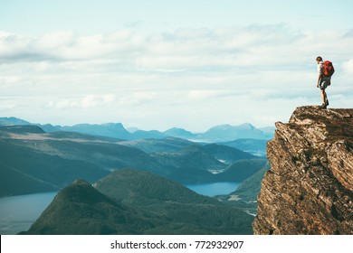 Man explorer standing on cliff alone mountain summit over fjord Norway landscape Travel Lifestyle success motivation concept adventure active vacations outdoor - Shutterstock ID 772932907