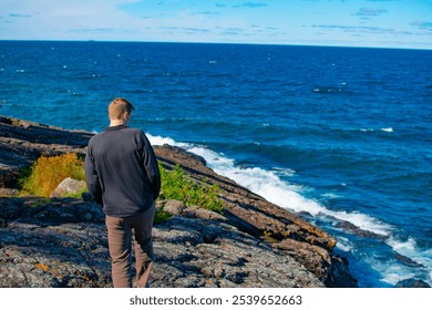 A man explores Black Rocks Beach in the upper peninsula of Michigan on a sunny day - Powered by Shutterstock