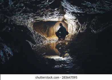 Man Exploring Cave Colorful Light