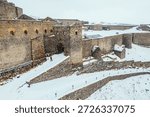 Man exploring Kars Castle in winter aerial view with snow. Traveler climbing to historic medieval fortress at snowy landscape in Turkey.