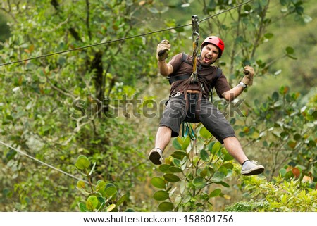A man in an extreme outdoor adventure, ziplining through the jungle canopy on a thrilling zip line.
