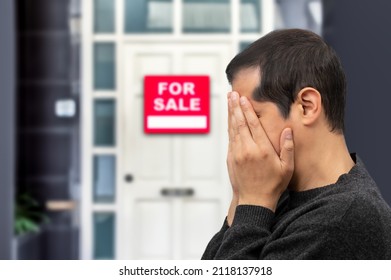 Man extremely depressed and sad about losing his house key and seeing a for sale sign, real estate concept