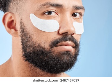 Man, eye pad and beauty in studio portrait with product for anti aging, cosmetics or skincare by blue background. Model, person and patch for dermatology, change and health with facial transformation - Powered by Shutterstock