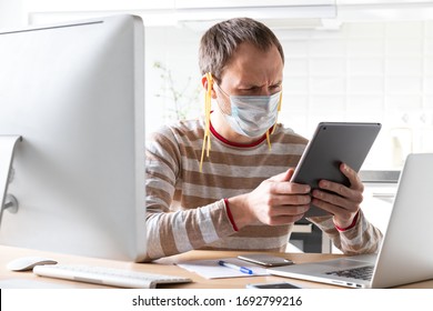 Man In Face Mask With Noodles On His Ears, Reads Fake/breaking News And A Speech By The President On Tablet About Coronavirus During Self-isolation, Quarantine. Desinformation, Lies In Social Media