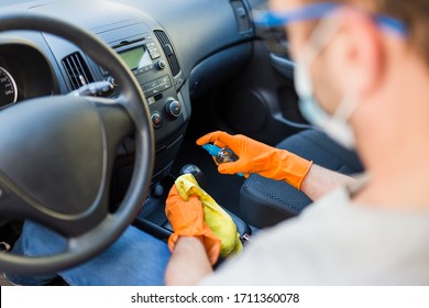 Man With Face Medical Mask Using Microfiber Cloth And Spray Bottle While Cleaning Car Interior Gear Stick.