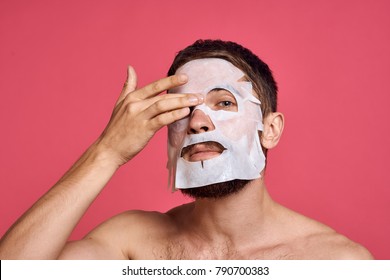  man in a facial mask for facial skin care on a pink background                             