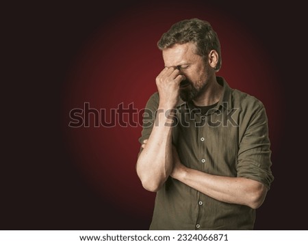 Man facing personal problems and challenges. Mid-aged man with closed eyes, conveying sense of sadness and inner turmoil. Isolated on dark red background, feeling of despair and emotional struggle