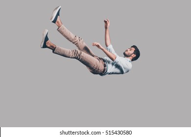 Man falling down. Mid-air shot of handsome young man falling against grey background  - Shutterstock ID 515430580