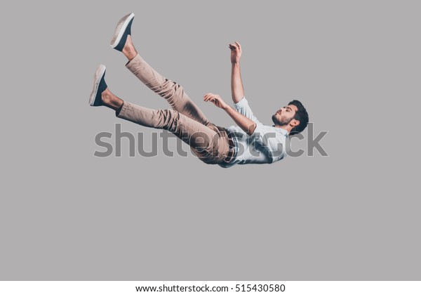 Man falling down. Mid-air shot of\
handsome young man falling against grey background\
