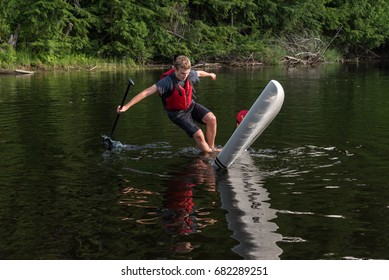 Man Falling Off Stand Up Paddle Board, Muskoka, Ontario, Canada.