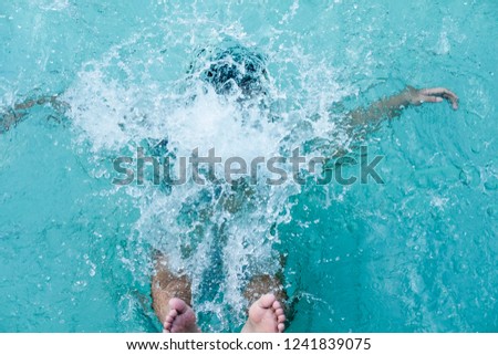 a man falls into a blue swimming pool, splashes of water