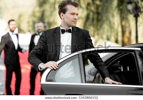 Man as a\
famous movie actor getting out the luxury car, arriving on the\
awards ceremony or movie premiere\
outdoors