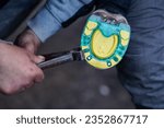 Man farrier installing plastic horseshoe to hoof. Closeup up detail to hands holding animal feet and metal tongs