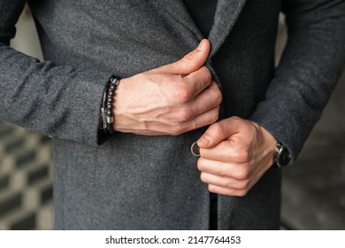 A Man Fastens A Button On A Gray Coat Jacket. Stylish Men's Accessories Up Close. Businessman Holds Hands Together.